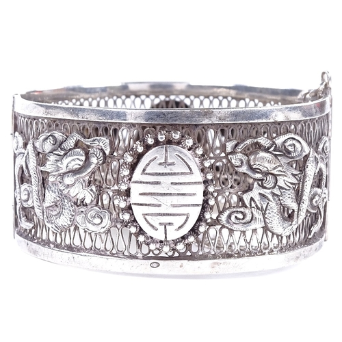 478 - An Antique Chinese silver hinged bangle, openwork body with relief applied dragon decoration and cen... 