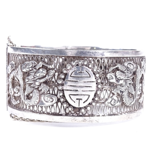 478 - An Antique Chinese silver hinged bangle, openwork body with relief applied dragon decoration and cen... 