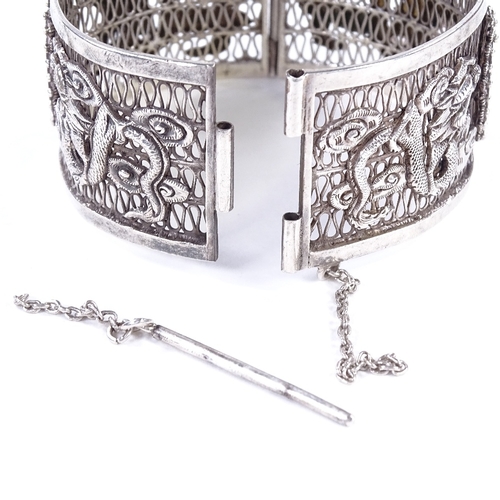 478 - An Antique Chinese silver hinged bangle, openwork body with relief applied dragon decoration and cen... 