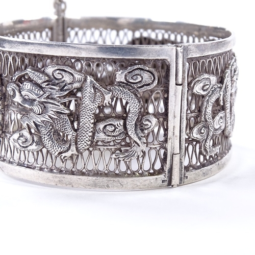 478 - An Antique Chinese silver hinged bangle, openwork body with relief applied dragon decoration and cen... 