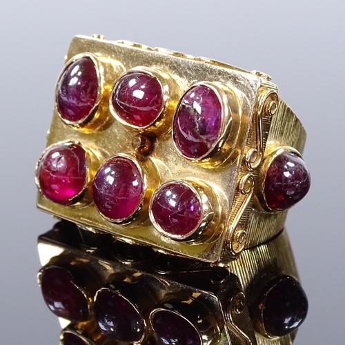 486 - An Eastern unmarked gold cabochon ruby cluster panel ring, scrollwork border and ribbed cabochon rub... 