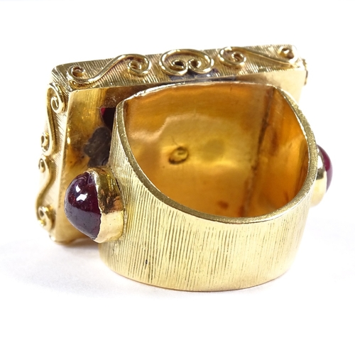 486 - An Eastern unmarked gold cabochon ruby cluster panel ring, scrollwork border and ribbed cabochon rub... 