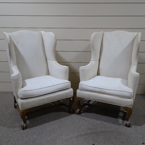 303 - A pair of Queen Anne style upholstered wing armchairs, on carved walnut bases with ball and claw fee... 