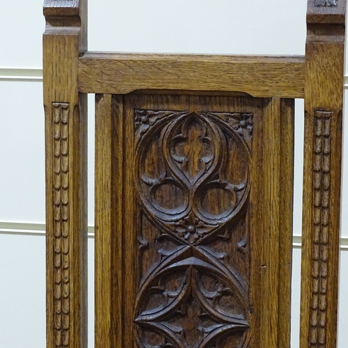 320 - A pair of Gothic style oak hall chairs, with relief carved tracery panelled backs