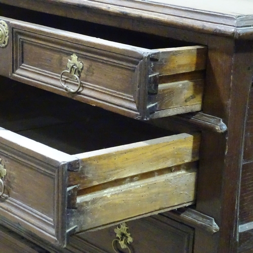 321 - An 18th century joined oak chest of 4 long drawers, with panelled drawer fronts and bracket feet, wi... 