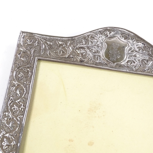 709 - An Indian unmarked silver-fronted photo frame, with relief embossed foliate decoration and hardwood ... 