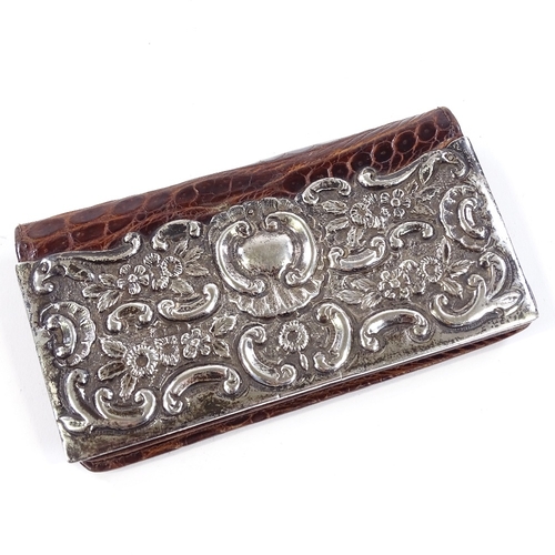 713 - An Edwardian silver-mounted crocodile bi-fold lady's purse, with relief embossed foliate and floral ... 