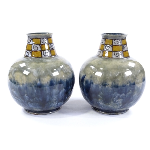 86 - A pair of Royal Doulton squat vases, mottled blue glaze with chequered swirl flared neck, impressed ... 