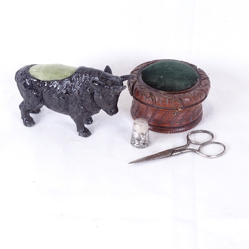 147 - A painted bull pin cushion, a sterling silver thimble, turned wood pin cushion etc