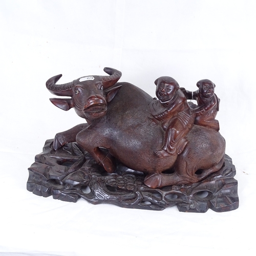 228 - An Oriental hardwood figure of 2 boys riding a water buffalo, on fitted carved and pierced stand, st... 