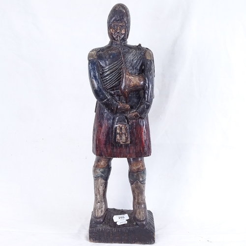 255 - A carved and painted wood sculpture, depicting Scotsman playing bagpipes, overall height 56cm