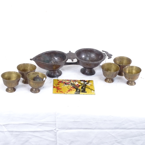 289 - An Eastern bronze double scent bowl, 6 brass cups, and an Oriental enamelled panel on metal (3)