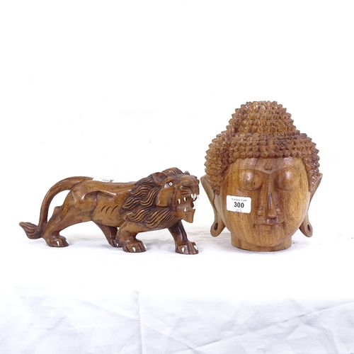 300 - An Oriental carved hardwood Buddha head, and a carved hardwood lion, head height 21cm (2)