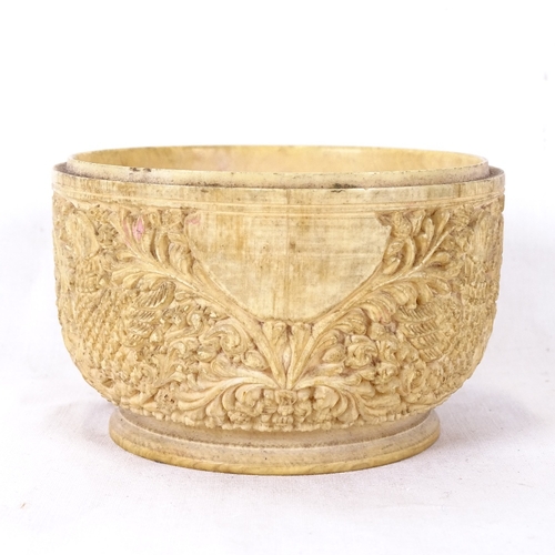 137 - A carved and polished circular ivory pot, relief foliate Buddha designs, diameter 10cm