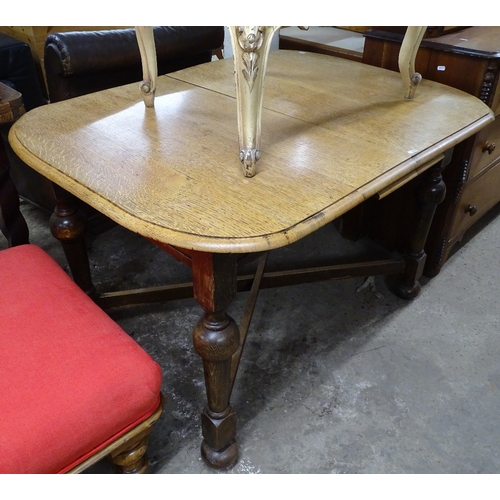 1503 - A 1920s oak round-cornered pop-up extending dining table on cross stretchers, with turned baluster l... 