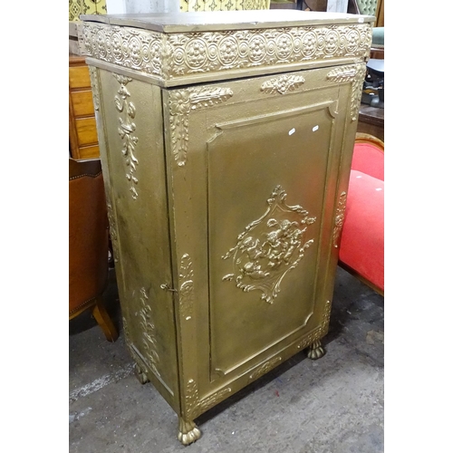 1506 - A gold painted cabinet, with carved frieze, panelled door with applied cherub mounts, opening to rev... 