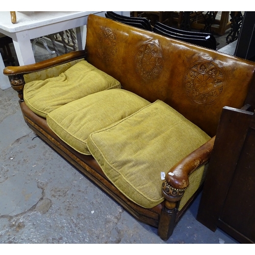 1555 - A 1920s tooled leather upholstered low 3-seater settee, with brass studwork, loose cushions, on bund... 