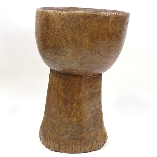 79 - A floor standing Tribal mortar bowl, carved from a single piece of wood, height 73cm, diameter 47cm