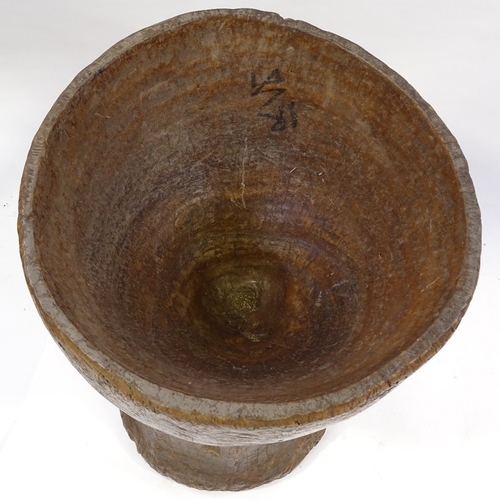 79 - A floor standing Tribal mortar bowl, carved from a single piece of wood, height 73cm, diameter 47cm