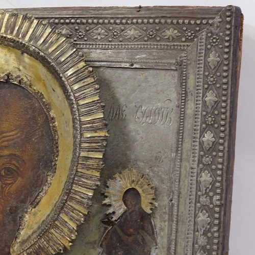 104 - A Russian silver-fronted icon, 18th or 19th century, painted portrait of a saint with Cyrillic inscr... 