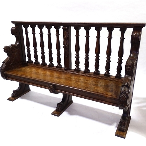 445 - A 19th century carved oak hall settle with spindle-back and lion paw feet, length 158cm