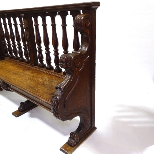 445 - A 19th century carved oak hall settle with spindle-back and lion paw feet, length 158cm