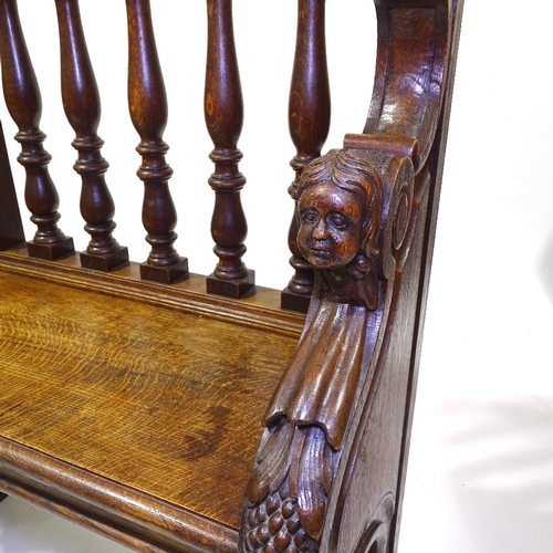 445 - A 19th century carved oak hall settle with spindle-back and lion paw feet, length 158cm