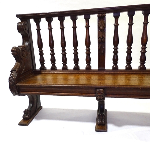 445 - A 19th century carved oak hall settle with spindle-back and lion paw feet, length 158cm