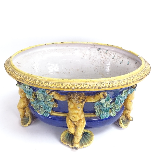 22 - A large 19th century glaze Majolica pottery jardiniere, with supporting cherubs and grapevine swags,... 