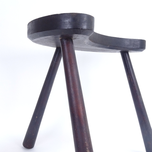 23 - A stained and penned hardwood curved tripod stool, height 36cm