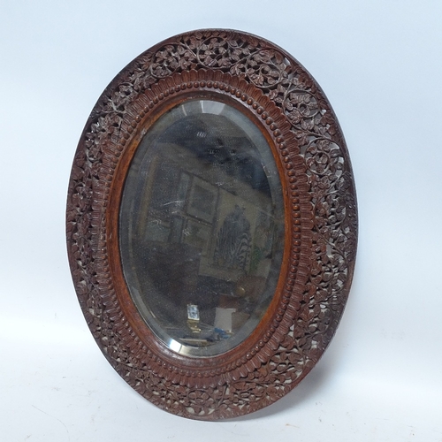 475 - A carved and pierced hardwood framed oval mirror, height 47cm