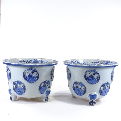 32 - A pair of Japanese Meiji period blue and white porcelain jardinieres, with relief flower panels and ... 