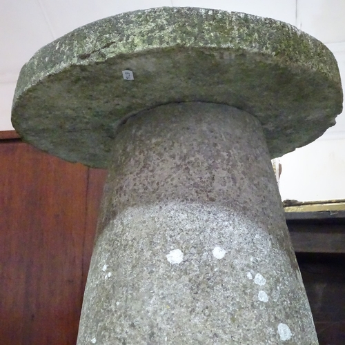 117 - A weathered stone saddle stone, height 74cm, diameter 41cm