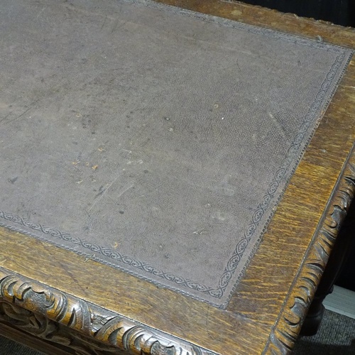 96 - A Victorian Carolean style oak library writing table, with frieze drawers, inset leather top on carv... 