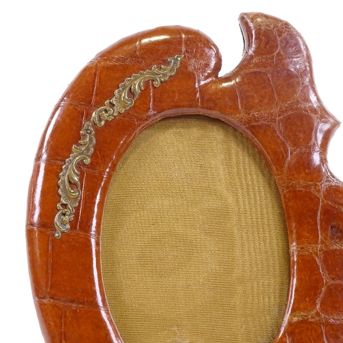 66 - A Victorian crocodile skin-covered photo frame, with shaped surround and brass mount, height 24cm