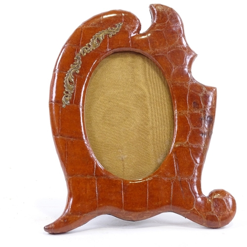 66 - A Victorian crocodile skin-covered photo frame, with shaped surround and brass mount, height 24cm