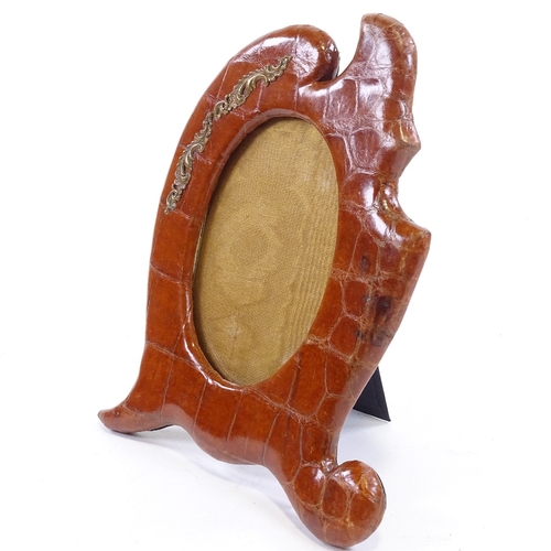 66 - A Victorian crocodile skin-covered photo frame, with shaped surround and brass mount, height 24cm