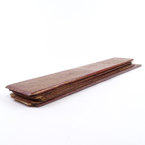 68 - A 19th century Burmese palm leaf prayer book, with gilded and lacquered wood covers, length 55cm