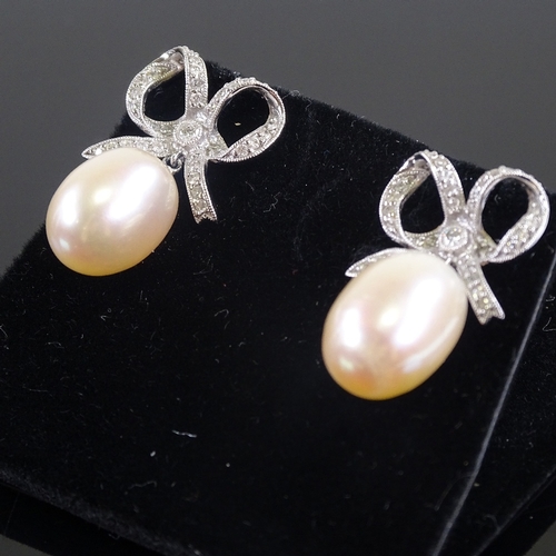 618 - A pair of unmarked white gold diamond and pearl bow drop earrings, earring height 26.3mm, 8.7g total