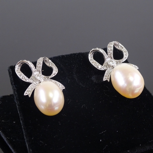 618 - A pair of unmarked white gold diamond and pearl bow drop earrings, earring height 26.3mm, 8.7g total