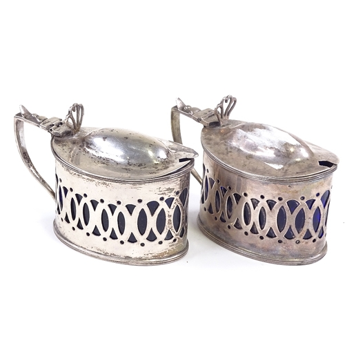 628 - A pair of late Victorian silver mustard pots, pierced decoration with blue glass liners and heart th... 