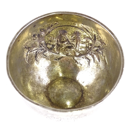 646 - An early 18th century German unmarked parcel gilt silver tumbler cup, relief embossed maiden playing... 