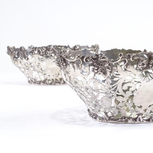 695 - A late Victorian pair of silver grape baskets, pierced foliate decoration with cast grapevine border... 