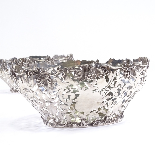 695 - A late Victorian pair of silver grape baskets, pierced foliate decoration with cast grapevine border... 