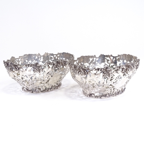 695 - A late Victorian pair of silver grape baskets, pierced foliate decoration with cast grapevine border... 