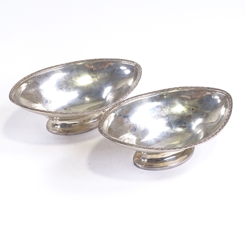 696 - A pair of George V silver boat-shaped pedestal bowls, engraved star rim, by Hukin & Heath, Jubilee h... 