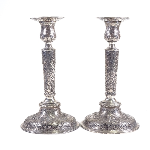 701 - A pair of 19th century German Hanau silver table candlesticks, allover engraved and embossed cherub ... 