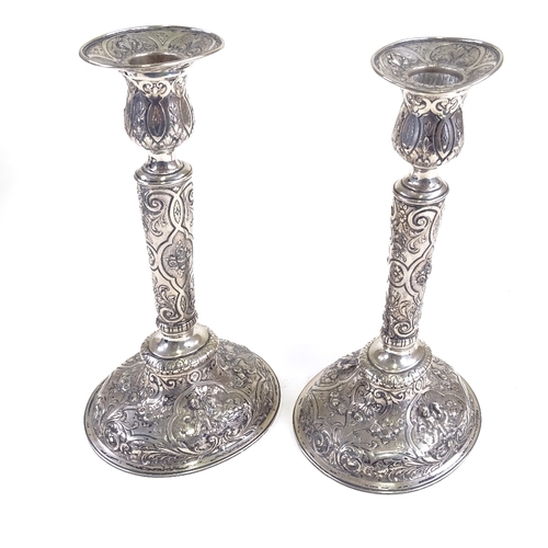 701 - A pair of 19th century German Hanau silver table candlesticks, allover engraved and embossed cherub ... 