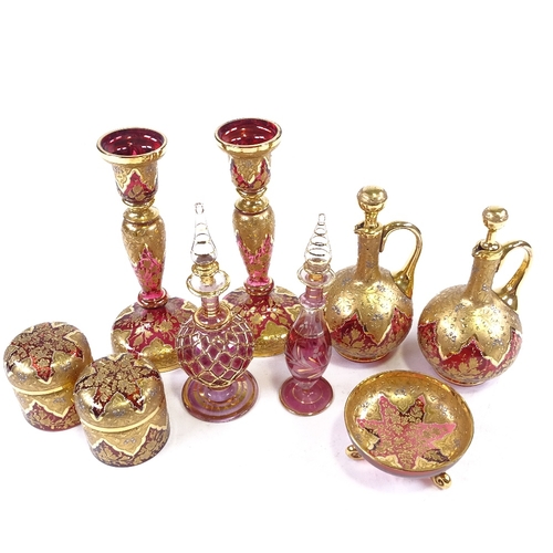 180 - A collection of mainly 19th century gilded Bohemian ruby glassware, including a pair of candlesticks... 