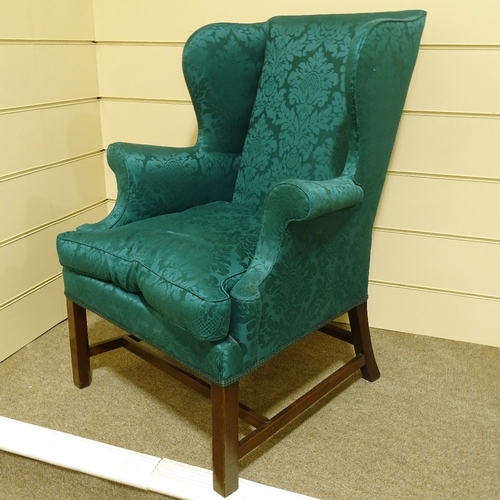 115 - A George III mahogany-framed upholstered wing armchair, with chamfered square legs, upholstered in d... 